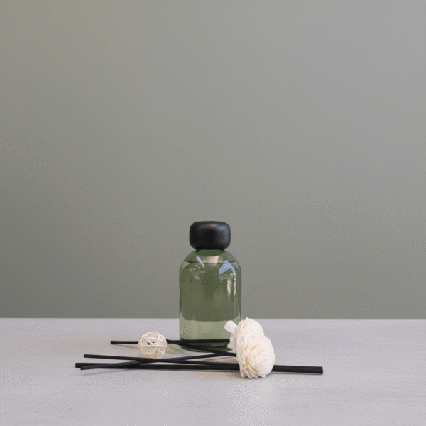 Modern sage green reed diffuser with decorative flower toppers, matte black cap, and black diffuser sticks, sage green reed diffuser available at Mint LB Zahle Lebanon